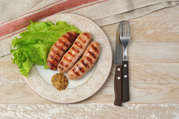 Grilled fried wurst on plate with salad leaves and peppers