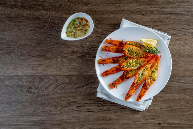 Grilled garlic butter prawns in a plate on a wooden table