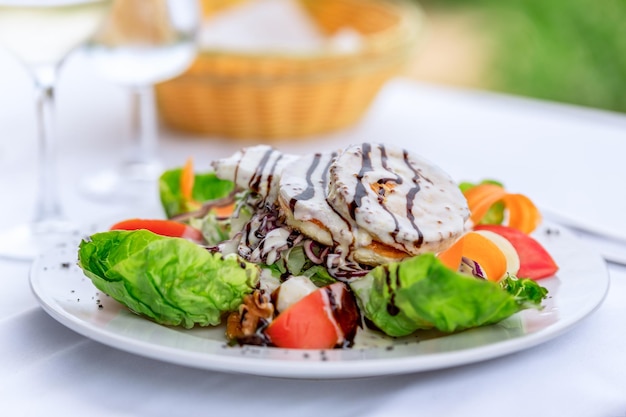 Grilled goat cheese with cream and balsamic sauce and fresh vegetable garnish