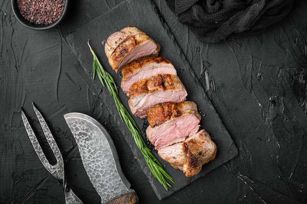 Grilled goose breast on stone serving board on black stone\
background top view flat lay with copyspace and space for text