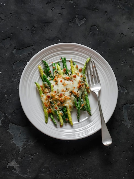 Grilled green string beans with mozzarella and lemon bread crumbs on a dark background top view