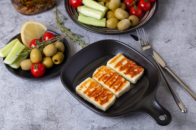 Formaggio haloumi alla griglia su una padella nera con olive, pomodori, cetrioli e peperoni. avvicinamento.