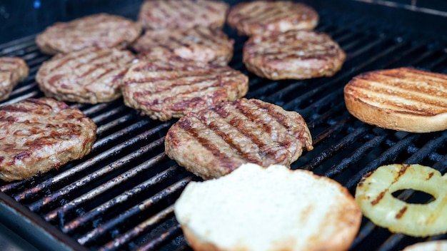 Foto carne e panini di hamburger alla griglia con ananas su una griglia bbq in acciaio inossidabile con fiamme