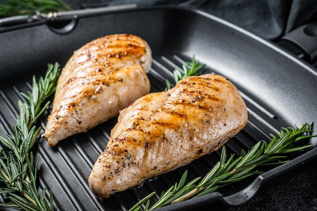 Grilled healthy chicken breasts cooked on a grill pan. Black background. Top view.