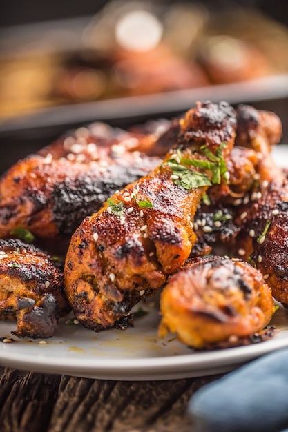 Grilled hicken legs BBQ with spices herbs and sesame on baked paper. Roasted poultry meal on white plate.