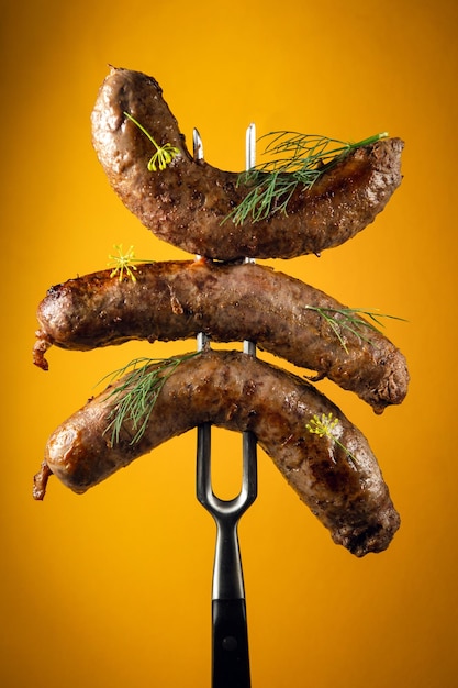 Grilled homemade meat sausages with dill on a fork Delicious lunch idea on yellow background