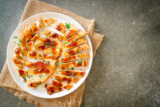 白い皿にスライスした蜂蜜チキン胸肉のグリル
