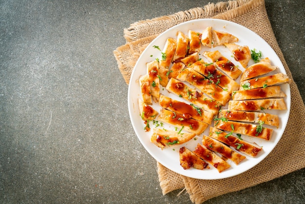 白い皿にスライスした蜂蜜チキン胸肉のグリル