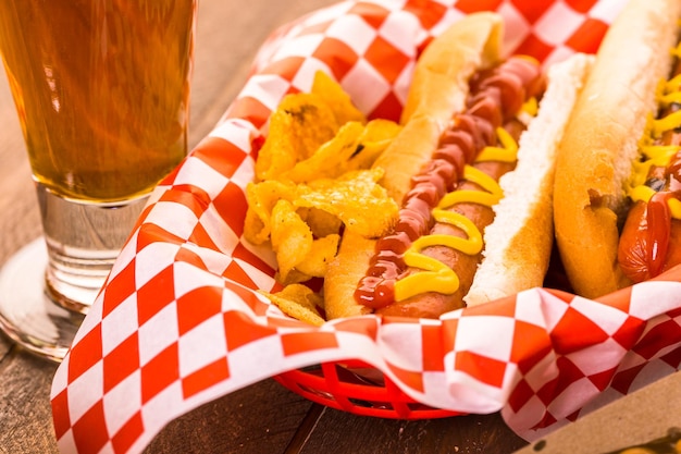 Grilled hot dogs with mustard and ketchup on the table with draft beer.