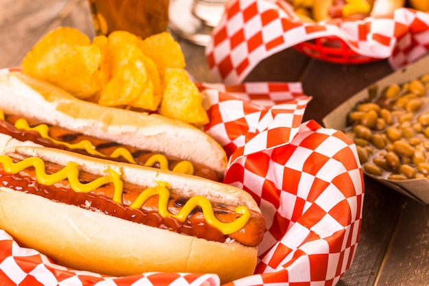 Grilled hot dogs with mustard and ketchup on the table with draft beer.