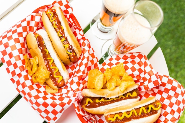 Grilled hot dogs with mustard and ketchup on the table with draft beer.