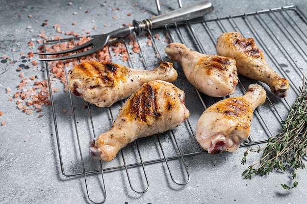 Grilled Jerk Chicken on a grill, leg drumstick poultry meat. Gray background. Top view.