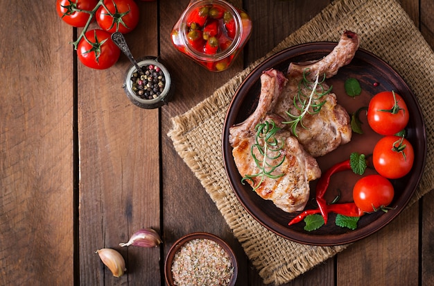 Grilled juicy steak on the bone with vegetables on a wooden background. Top view