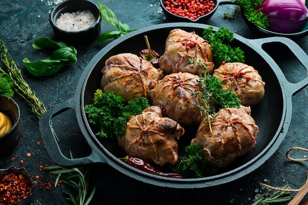 Grilled juicy turkey cutlets in a pan with spices and herbs on\
a black stone background top view