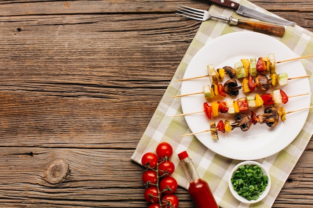 写真 木製のテーブルの上の白い皿に焼きケバブ串