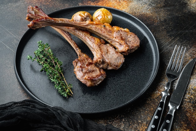 Grilled lamb chops with orange and carrot set, on plate, on old dark rustic table