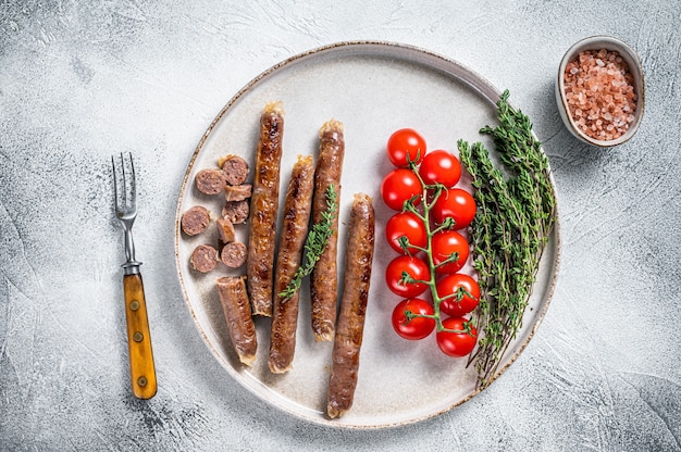 Grilled lamb meat sausage on a plate with herbs and tomato.