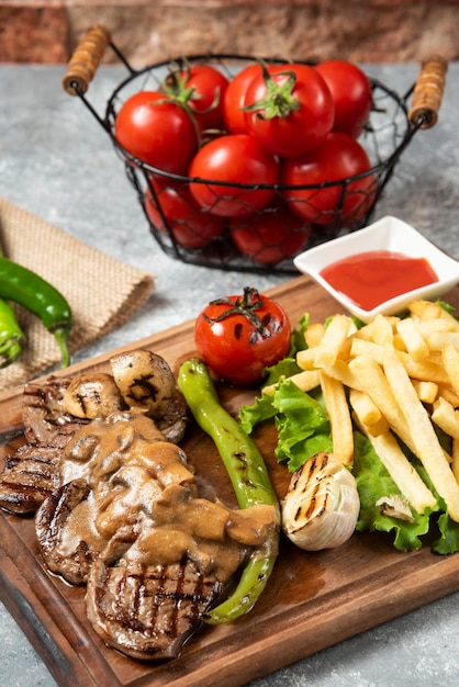 Foto carne di agnello alla griglia con patatine fritte su piatto di legno