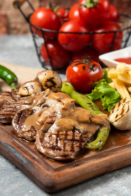 Foto carne di agnello alla griglia con patatine fritte su piatto di legno