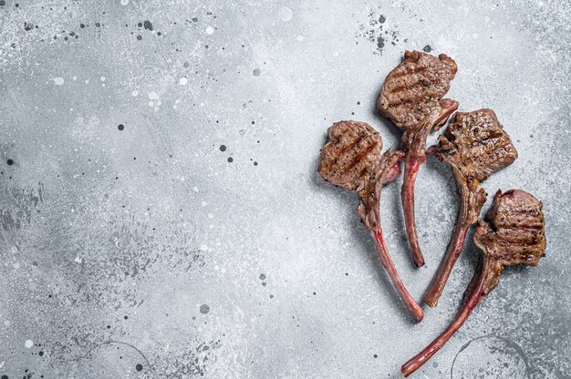 Grilled lamb mutton meat chops steaks. Gray background. Top view. Copy space.