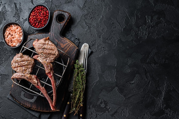 La carne di montone di agnello alla griglia taglia le bistecche alla griglia. sfondo nero. vista dall'alto. copia spazio.