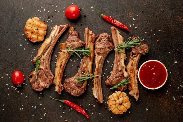 Grilled lamb ribs with spices and garlic on a stone background