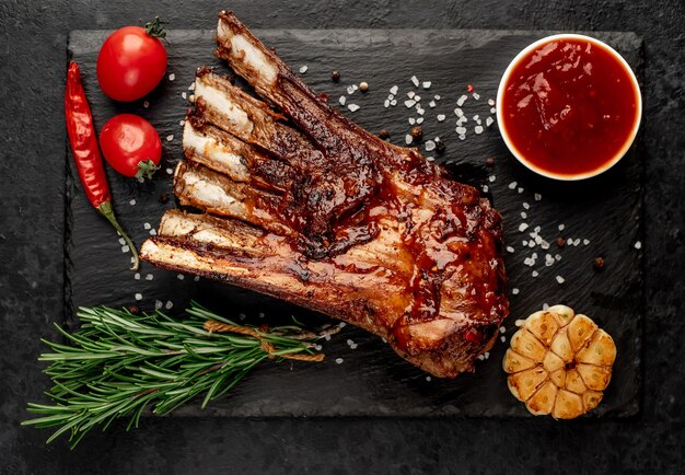 Grilled lamb ribs with spices and garlic on a stone background