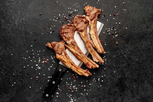 Grilled lamb ribs with spices on a knife on a stone background  