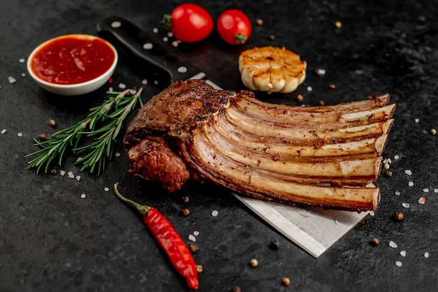 Grilled lamb ribs with spices on a knife on a stone background  