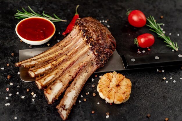 Grilled lamb ribs with spices on a knife on a stone background  