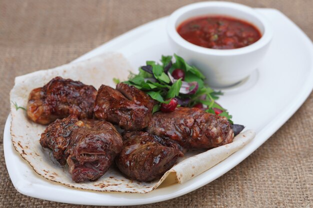 Grilled lamb skewers on a white plate