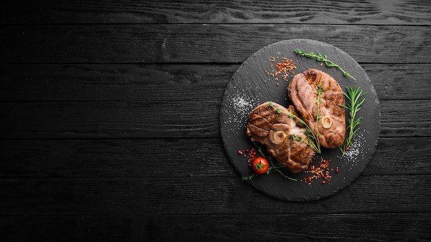 Grilled lamb steak with spices and rosemary Barbecue meat Top view Flat lay top view on black stone cutting table