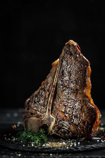 grilled large t-bone steak garnished. F Close up. vertical image