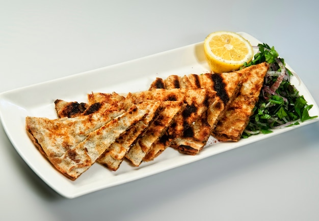 Grilled lavash sliced on black plate Armenian flatbread lavash wraps on wooden background
