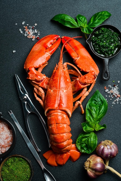 grilled lobster with lemon and basil on a black slate board on a dark wooden table