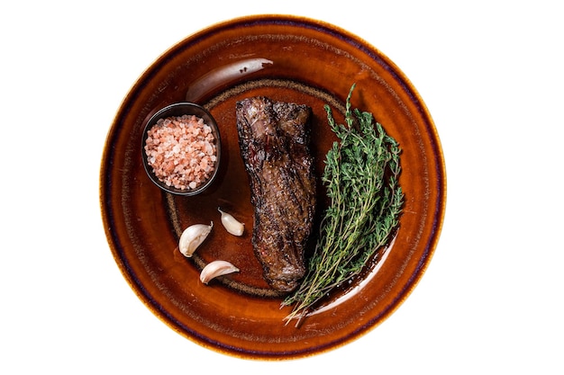 Grilled machete skirt beef steak on rustic plate with herbs and pink salt Isolated on white background