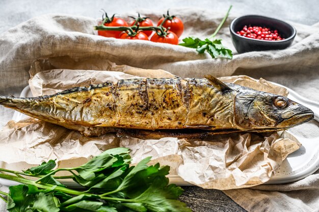 Grilled mackerel with parsley and cherry tomatoes. Gray background. Top view