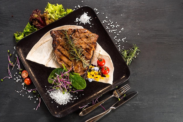 Grilled marble steak dish on black background