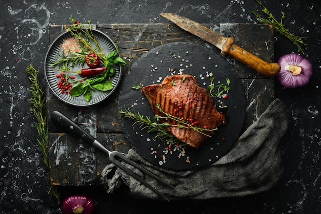 Grilled marbled beef steak tenderloin On a black stone background