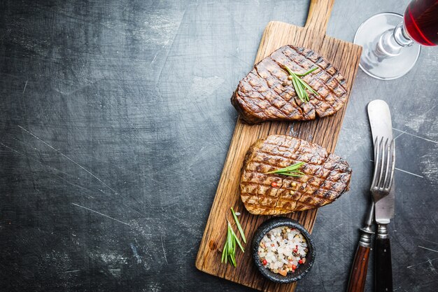 霜降り肉のグリルフィレミニョンと調味料。まな板の上にジューシーなビーフステーキ、上面図。