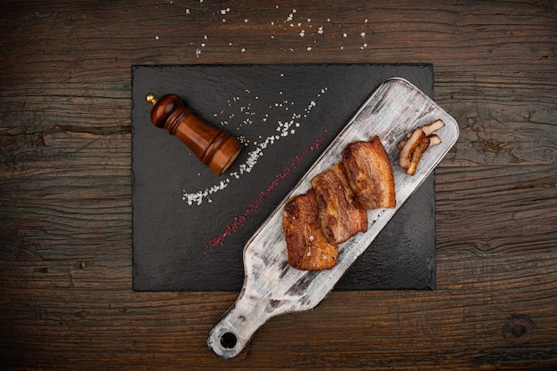 Grilled meat is placed on a black stone dish Next to the knife salt and pepper shaker