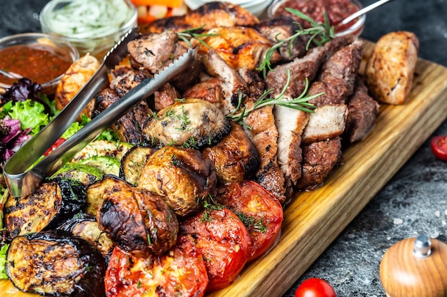 Photo grilled meat platter and vegetables on tray. grill barbecue menu. restaurant menu, dieting, cookbook recipe