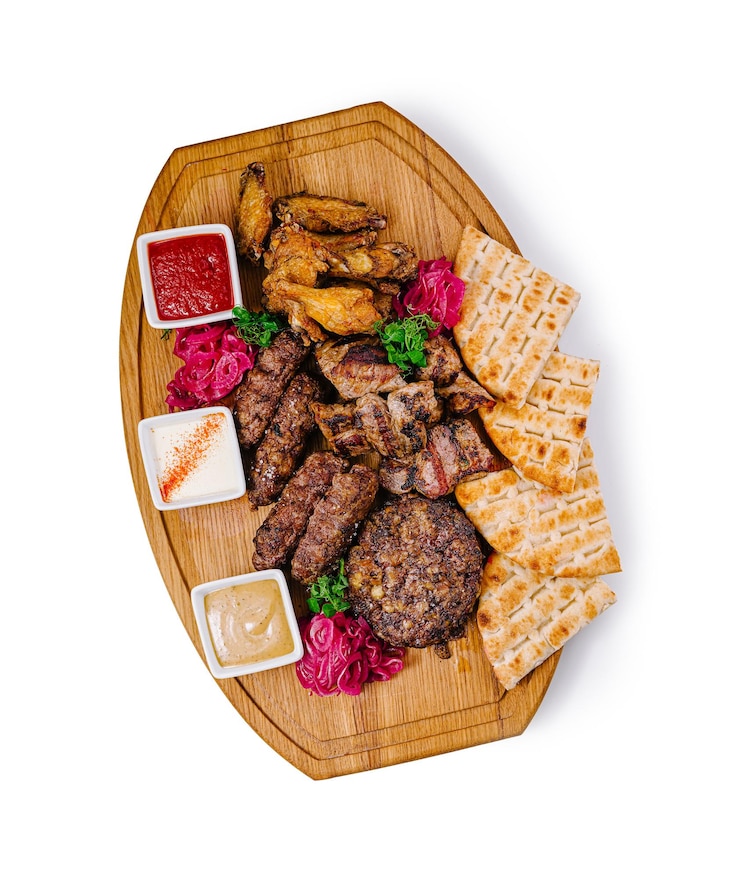 Photo grilled meat platter with chicken wings sausages burger pita bread and sauces on wooden board
