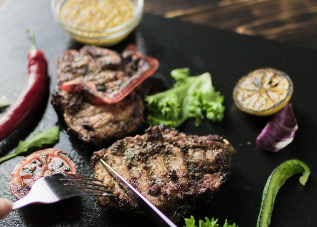 Grilled meat served with vegetables spices on a slate plate