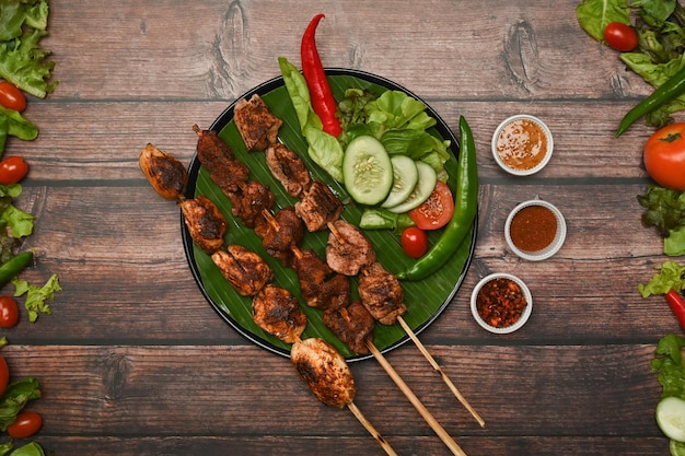 Grilled meat skewers in round plate surrounded by Sichuan pepper Chinese spices and vegetable on wooden table