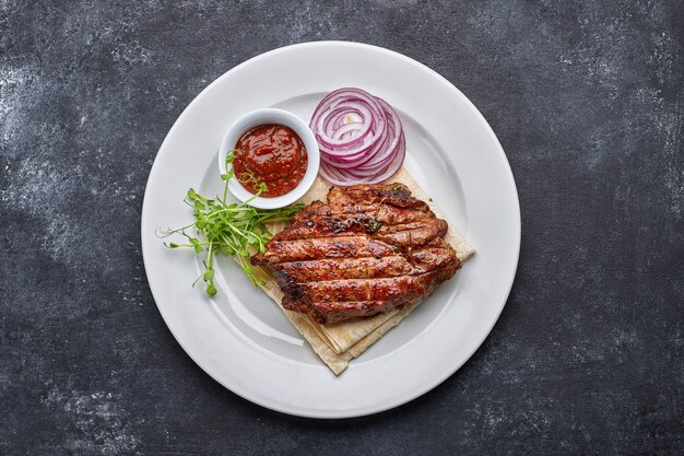 Grilled meat steak with onions, sauce and microgreen