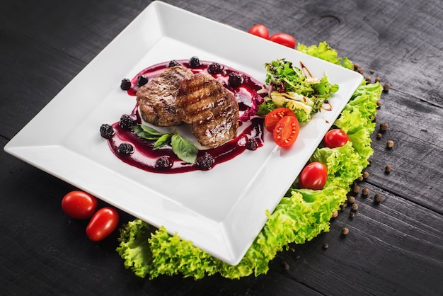 Grilled meat steak with raspberry sauce on wooden