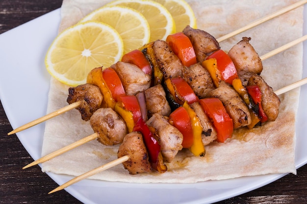 Grilled meat and vegetables on skewer in the plate close up