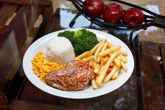 Grilled meat with rice, corn, chips and broccoli