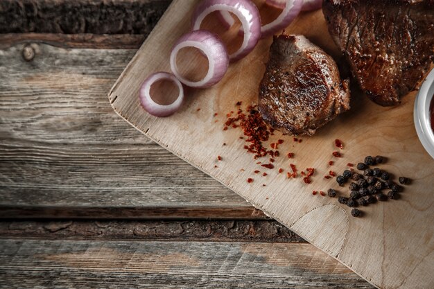 Мясо на гриле со специями и томатным соусом на изношенных деревянных фоне